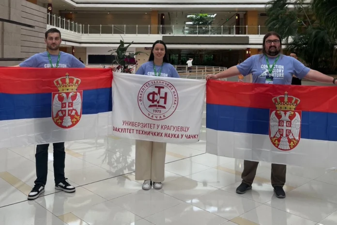 Tri srpska studenta drže zastavu Srbije i zastavu Fakulteta tehničkih nauka iz Čačka nakon osvajanja nagrade na Huawei ICT takmičenju 2024/2025.